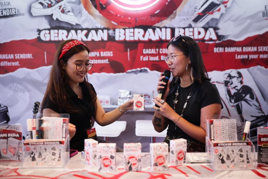 Dua pengunjung di booth Lucky Tribe dengan latar mural Gerakan Berani Beda